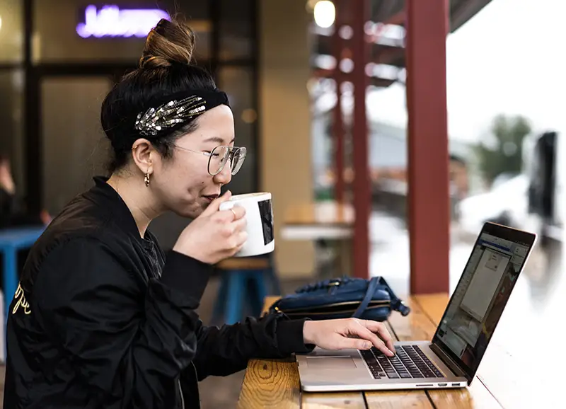 노트북을 사용하여 커피를 마시는 여자